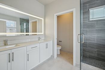 a bathroom with white cabinets and a shower and a sink at The Falls of Portofino Apartment, Naples, 34119